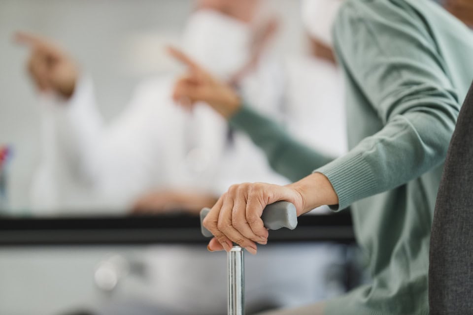 An older hand gripping a walking cane